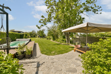a backyard area with an umbrella and some plants in the foreground, on a bright sunny day there is a...