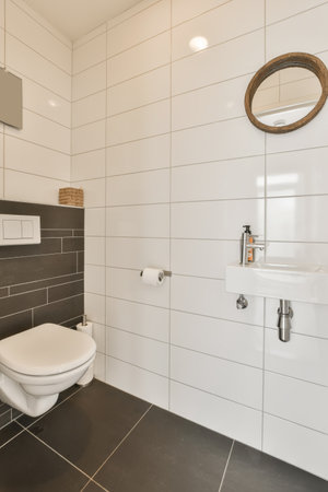 a modern bathroom with black and white tiles on the walls, toilet and sink in the room is very cleanの写真素材