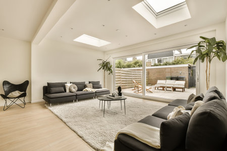 a living room with wood flooring and skylights on the ceiling, there is a black sofa in front