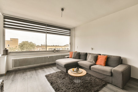 a living room with a couch, coffee table and large window looking out onto the cityscaped view