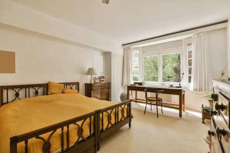 a bedroom with a bed, desk and television in the corner area on the right hand side of the room