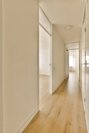 an empty room with white walls and wood flooring on the right side of the room, there is a door leading to anotherの写真素材