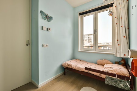 a small room with a bed, window, and lamp on the right hand side of the room is an open door