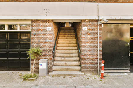 a brick building with two garages on the front and stairs leading up to the second floor in an alley