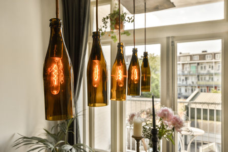 some wine bottles hanging from the ceiling over a dining room table with flowers in vases and candles on itの写真素材