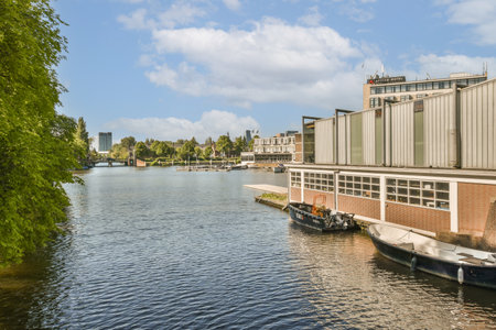 some boats in the water and buildings on the other side of the river, with blue skies overhead above themの写真素材