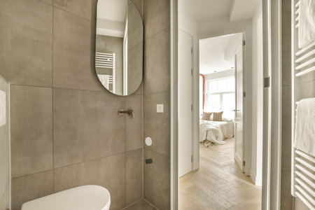 a bathroom with a toilet, mirror and towel rack on the wall next to the bathtub in the roomの写真素材