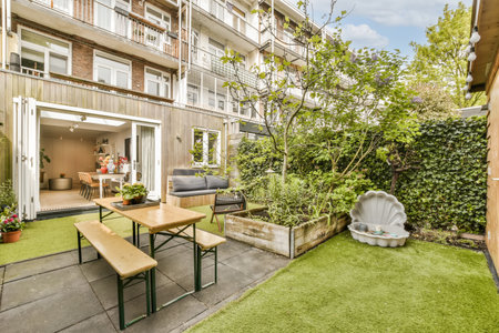 an outdoor living area with green grass and wooden furniture in the back yard is surrounded by plants, shrubs and treesの写真素材