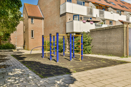 an outdoor play area in front of a brick building with blue and yellow playground equipment on the...