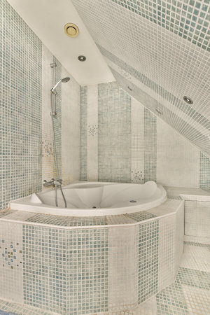 a bathroom with blue and white mosaic tiles on the walls, along with a freestanding bathtub in the...