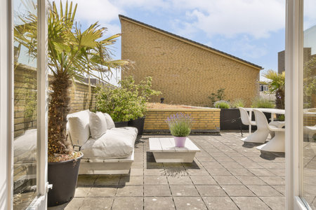 an outside area with furniture and plants in the fore - image is taken from inside, but no one can...