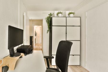 a room with a desk, chair and computer monitor on the wall next to it is an open door that leads to...