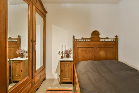 a bedroom with a bed, dresser and mirror on the wall above it that is in front of the doorの写真素材