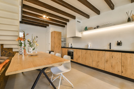 a kitchen and dining area in a house with wood beams on the ceiling, white walls and wooden flooring