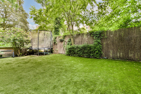 a backyard area with a fence and some green grass in the yard is surrounded by trees, shrubs and...