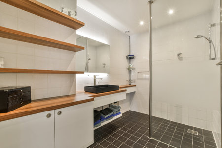 a bathroom with white tiles and wooden shelves on the wall, along with a glass shower stall in the...