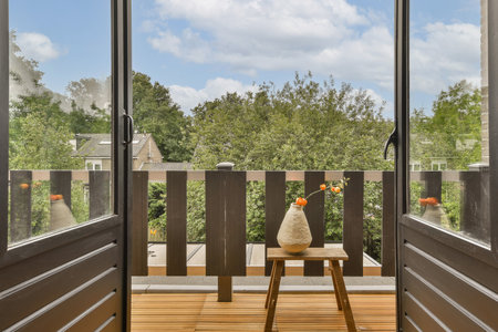 an outside area with wood flooring and wooden doors leading to the patio, looking out onto trees in the distanceの写真素材