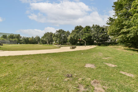 Vibrant park scene featuring a well-kept grassy area, trees in the background, and a clear blue sky,...