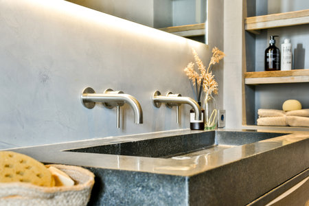 A stylish bathroom sink featuring sleek faucets, a stone countertop, and modern shelving, showcasing...