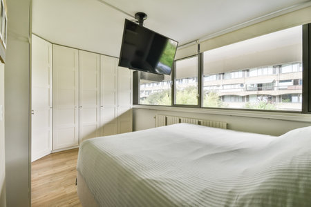 Bright and spacious bedroom featuring a comfortable bed and large windows overlooking an exterior...