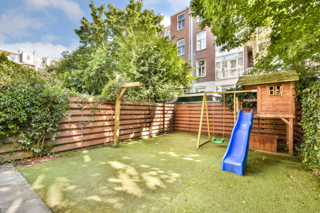 A vibrant backyard features a wooden playhouse, slide, and lush greenery, perfect for childrens...