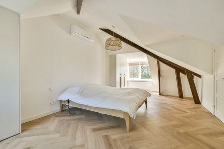 A spacious minimalist bedroom showcasing natural light, wooden flooring, and a cozy bed, reflecting...