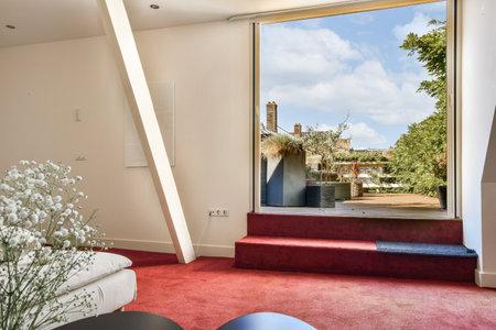 A contemporary living space featuring a large open window that showcases a lush outdoor view, complemented by elegant decor and bright, inviting colors.の写真素材