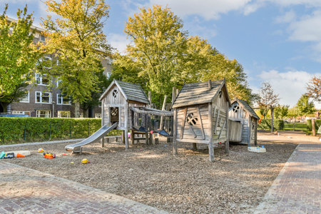 A vibrant playground features wooden structures, a slide, and surrounding lush trees under a bright...