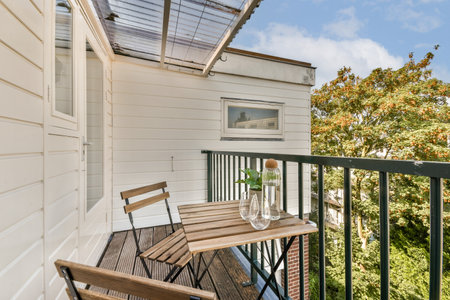 A stylish balcony featuring wooden furniture and a decorative plant. The setting is bright and airy,...