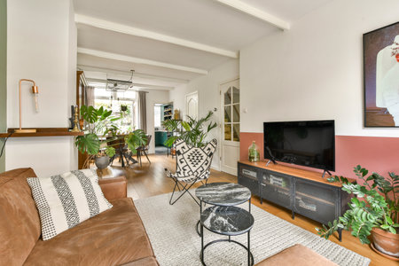 A stylish modern living room featuring plush seating, a wooden floor, and various indoor plants that...