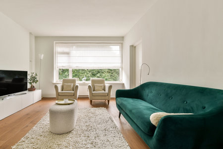 A stylish living room featuring a contemporary design with soft textures, green accents, and natural light streaming through a large window.の写真素材