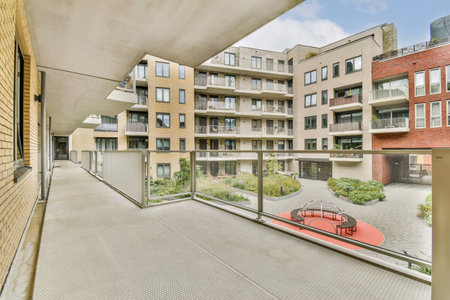 A contemporary apartment building view showcasing balconies, a courtyard garden, and modern...