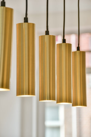 Stylish pendant lights with a sleek gold finish illuminate a contemporary interior. Ideal for enhancing modern decor with a touch of elegance.の写真素材
