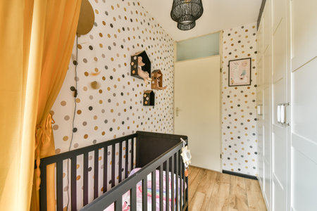 A charming nursery featuring polka dot wallpaper, a cozy crib, and warm golden accents. Ideal for a...