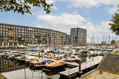 A vibrant marina scene showcasing various sailboats docked alongside modern architecture. Clear skies enhance the visual appeal of this lively waterfront.の写真素材