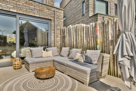 A modern patio featuring a comfortable lounge set surrounded by natural elements and wooden fencing, perfect for relaxation and outdoor gatherings.の写真素材