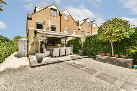 A stylish outdoor garden featuring modern furniture, lush greenery, and a well-designed layout for...