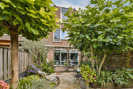 Lush greenery surrounds a cozy patio featuring flowering plants and a rustic seating area, perfect...