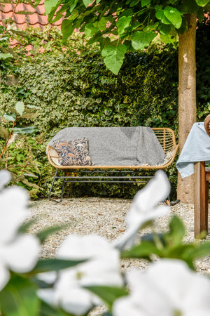 A tranquil garden scene featuring a comfortable seating area surrounded by lush greenery and vibrant flowers, perfect for relaxation or socializing.の写真素材