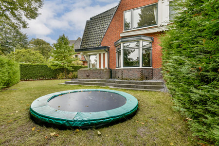 A vibrant backyard featuring a trampoline nestled amongst lush greenery, offering a playful atmosphere ideal for family activities and outdoor fun.の写真素材