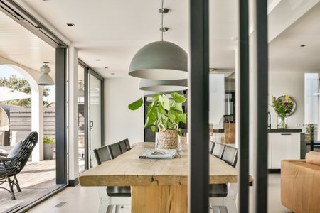 A stylish dining area featuring a large wooden table, sleek chairs, and abundant natural light from...