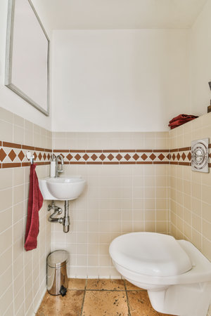 a white toilet in a small bathroom with tiled walls and brown tile on the floor, there is a mirror...