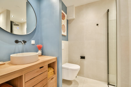 This beautifully designed modern bathroom features a stylish sink, wooden cabinetry, and sleek...