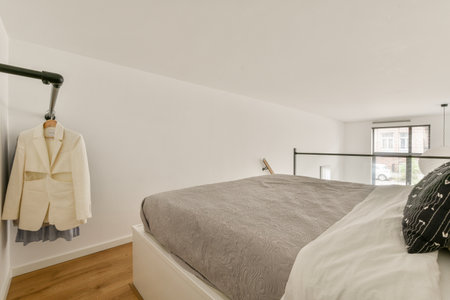 A serene and modern bedroom featuring a neatly made bed, stylish clothing hanging on a rack, and...