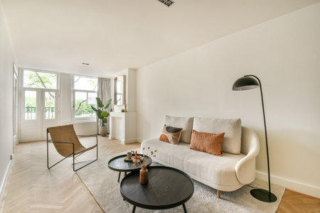 A bright and airy modern living room featuring a sleek sofa, stylish decor, and natural light...