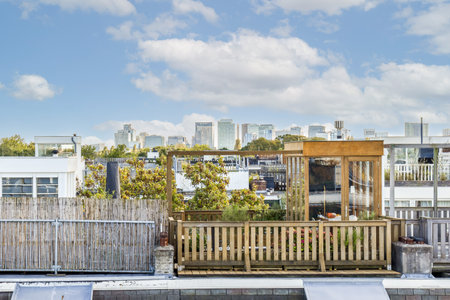 A beautifully designed rooftop garden featuring wooden elements, greenery, and a stunning skyline view of a modern city. Ideal for relaxation and urban escape.の写真素材