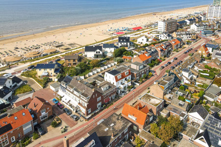 Featuring a charming coastal town, this aerial perspective showcases sandy beaches, residential areas, and vibrant beach activities, perfect for summer visits.の写真素材