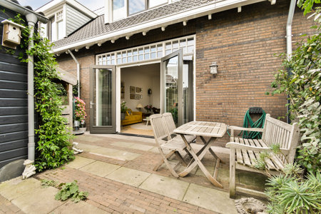 A cozy outdoor patio featuring wooden furniture and a brick wall of a contemporary house, adorned...
