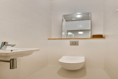 A sleek and modern bathroom featuring a wall-mounted toilet, minimalist sink, and neutral color scheme. The space emphasizes simplicity and functionality.の写真素材