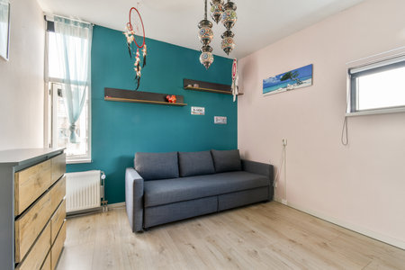 A contemporary living room featuring a stylish gray sofa, vibrant teal wall, and decorative elements...